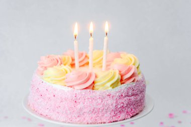 Güzel dekore edilmiş bir doğum günü pastasında pembe ve sarı renkli mumlar var..