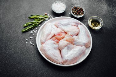 Baharatlı baharatlı tavuk kanatları ve koyu taşlı arka planda yağ.