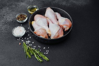 Siyah kasede çiğ tavuk budu ve baharat.