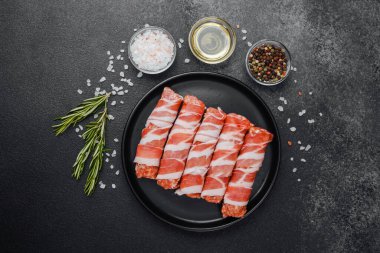 Domuz pastırmasına sarılı çiğ et ruloları ve baharatlar.