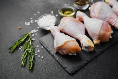 Siyah tahta üzerine yerleştirilmiş tavuk budu, otlar ve tuzlu.