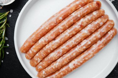 Beyaz tabakta taze domuz sosisi ve baharat.