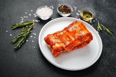 Beyaz tabakta marine edilmiş domuz pirzolası ve baharat.