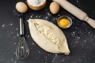 Pişmemiş khachapuri, siyah masada çırpılmış yumurta.