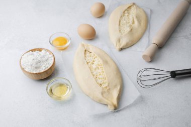 Işık yüzeyinde peynirli ve yumurtalı iki çiğ khachapuri.