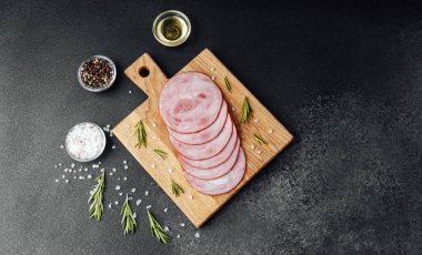 Siyah masa arkasında tuzlu ve biberiyeli dilimlenmiş domuz sosisi.