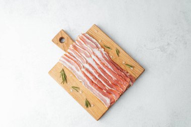 Ahşap tahtada çiğ pastırma dilimleri, biberiye ve koyu arkaplanda tuz.