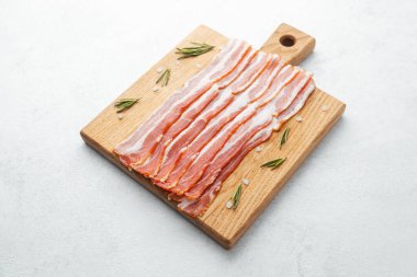 Ahşap tahtada çiğ pastırma dilimleri, biberiye ve koyu arkaplanda tuz.