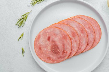 Beyaz tabakta dilimlenmiş sosis ve baharat.