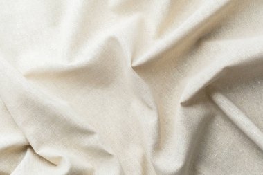 Yumuşak kıvrımlı ve desenli doğal bej kumaş.