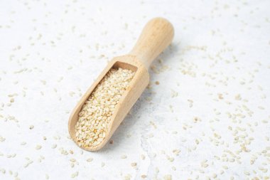 Hafif desenli yüzeyde susam tohumlarıyla dolu ahşap kepçe..