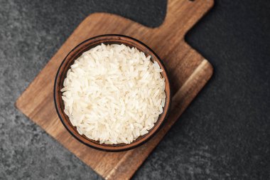 Mutfaktaki ahşap bir tahtanın üzerinde bir kasede pişmemiş beyaz pirinç sergileniyor..