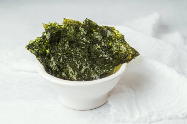 Tahta tahtada kızarmış Norveç yosunu ve beyaz ve yeşil arka planda seramik kase.