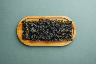 Ahşap tepside yeşil arka planda kızartılmış yosun atıştırmalığı.