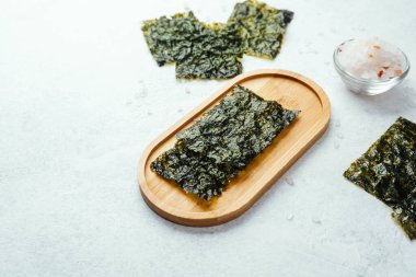 Beyaz arka planda bir kase tuzlu kavrulmuş yosun atıştırmalığı