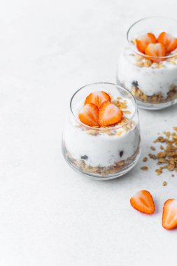 Dilimlenmiş çilek ve tahıl gevreğiyle kaplı yoğurt parfe.