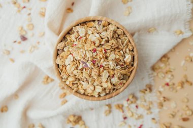 Tahta kasede yumuşak beyaz kumaş arka planda granola.