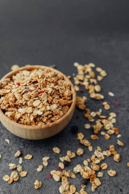Üst manzara granola kasede, koyu arkaplanda dağınık parçalar var.