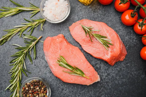 Siyah arka planda biberiyeli taze çiğ biftek ve tuz ve baharat.