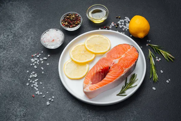 Limon dilimleri ve çeşitli baharatlarla birlikte beyaz bir tabağa konmuş somon filetosu..