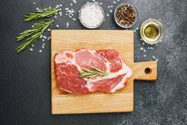 Biberiyeli çiğ biftek ve ahşap tahtada baharatlar.