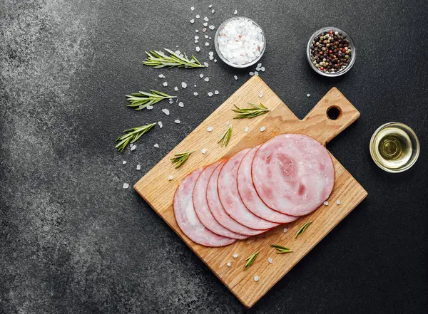 Siyah masa arkasında tuzlu ve biberiyeli dilimlenmiş domuz sosisi.