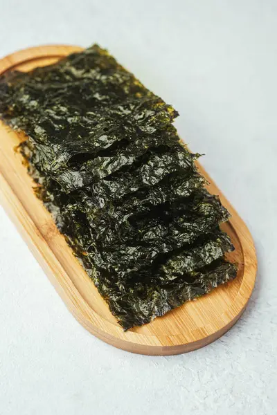 Ahşap tepside beyaz arka planda duran yosun parçaları.