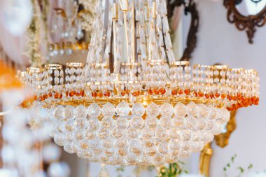 Şatafatlı bir avize dekoratif bir ortamda aydınlatılmış, ortamın havasını yükseltiyor..