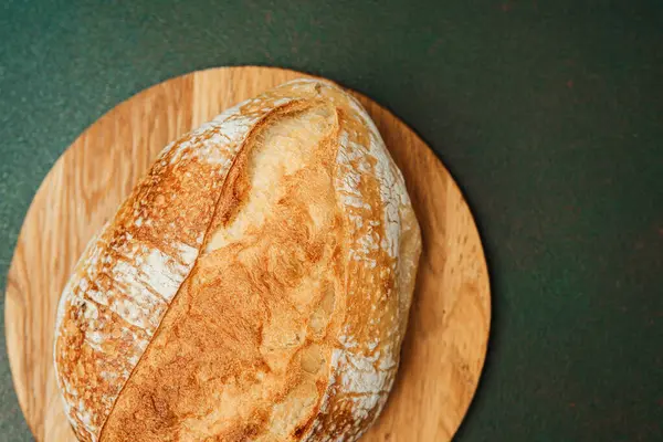 Güzel bir somun ekşi ekmek ahşap bir tahtanın üzerinde duruyor, eğlenmeye hazır..