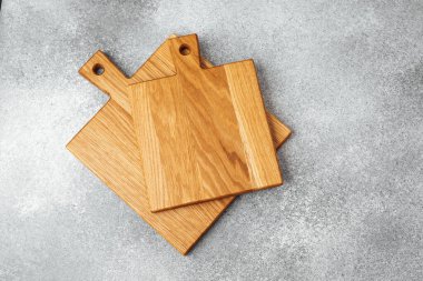 Mutfak işleri için gri bir yüzeye üç tahta kesme tahtası düzgün bir şekilde yerleştirilmiştir..