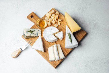 Tatma deneyimi için ahşap bir tahtaya yerleştirilmiş çeşitli peynir ve bal..