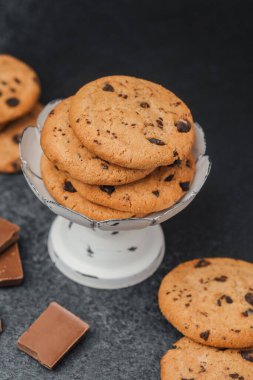 Çikolata parçalı kurabiyeler tezgahın üstünde, yanında çikolata parçacıkları var..