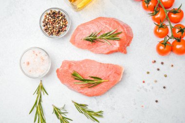 Beyaz arka planda baharatlı dana bifteği ve bitkilerin üst görüntüsü, yakın plan yağ ve biber dahil.