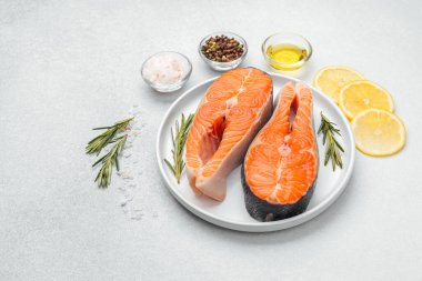 Limon dilimleri ve otlarla birlikte beyaz bir tabağa konmuş somon filetoları..