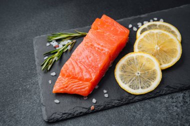 Limon dilimleri ve bitkilerle sunulmuş somon filetosu..