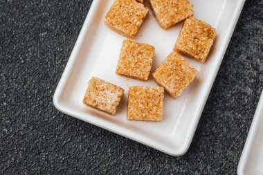 Kahverengi şeker küpleri servis için beyaz seramik bir tabakta gruplandırılır..