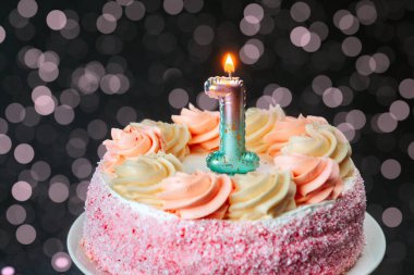 Pembe kremalı güzel dekore edilmiş bir pasta ve parlak bir mum..