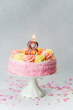 Sekiz mumlu pembe pasta bir çocuğun doğum gününü kutlar..