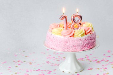 Krem şanti ve mumlarla kaplı pembe bir pasta 18. yaş günü kutlamasıdır..