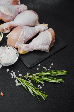 Siyah tahta üzerine yerleştirilmiş tavuk budu, otlar ve tuzlu.