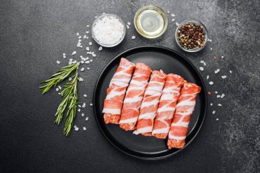 Domuz pastırmasına sarılı çiğ et ruloları ve baharatlar.