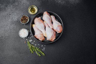 Siyah kasede çiğ tavuk budu ve baharat.