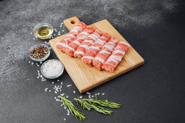 Pastırmaya sarılı çiğ et ruloları ahşap tahtaya baharatlı.