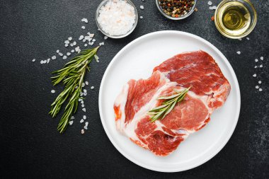 Biberiye ve baharatlı, beyaz tabakta pişmemiş biftek.