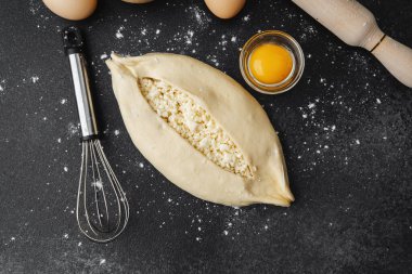 Pişmemiş khachapuri, siyah masada çırpılmış yumurta.
