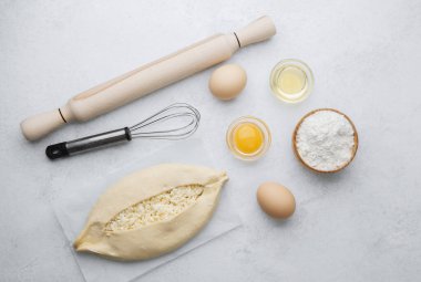 Beyaz zemin üzerinde yumurta sarısı ve peynirli çiğ khachapuri.