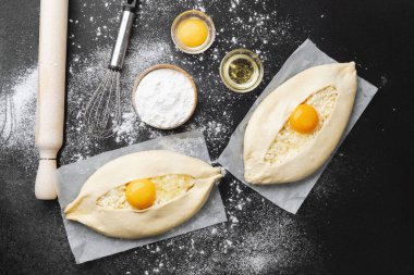 Un kaplı yüzeyinde yumurta sarısı olan iki çiğ khachapuri.