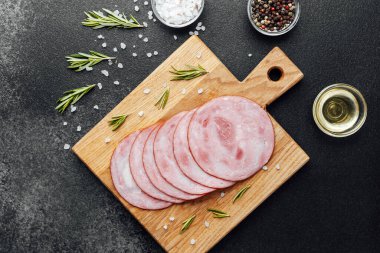 Siyah masa arkasında tuzlu ve biberiyeli dilimlenmiş domuz sosisi.