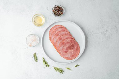 Beyaz tabakta dilimlenmiş sosis ve baharat.