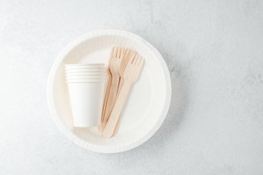 Beyaz tek kullanımlık tabakta beyaz kağıt bardaklar ve tahta çatallar.